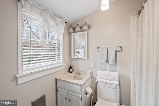 bathroom with walk in shower, vanity, and toilet