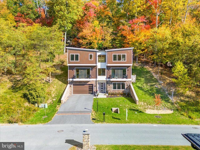 view of front of property with a front lawn, a garage, and a balcony