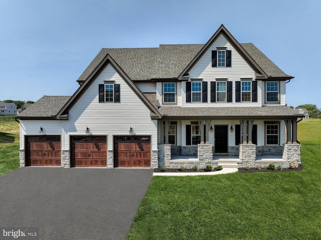 view of front of house featuring covered porch, driveway, a shingled roof, and a front yard