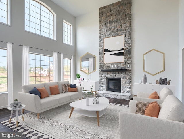 living room featuring a stone fireplace, wood finished floors, and a towering ceiling