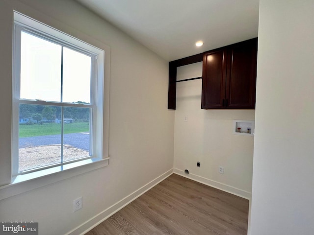 clothes washing area with washer hookup, hardwood / wood-style flooring, hookup for an electric dryer, and cabinets