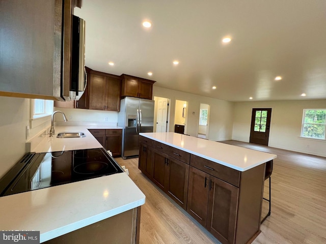 kitchen featuring light wood-type flooring, stainless steel fridge, a kitchen island, and sink