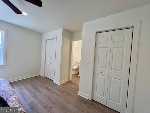 unfurnished bedroom with ceiling fan, multiple closets, and hardwood / wood-style flooring