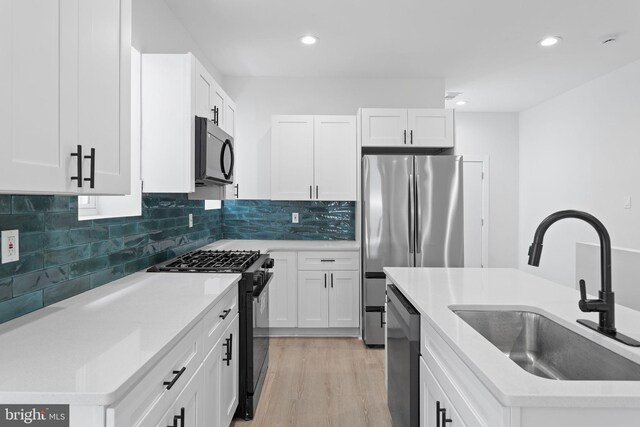 kitchen featuring black appliances, light hardwood / wood-style floors, white cabinetry, and sink