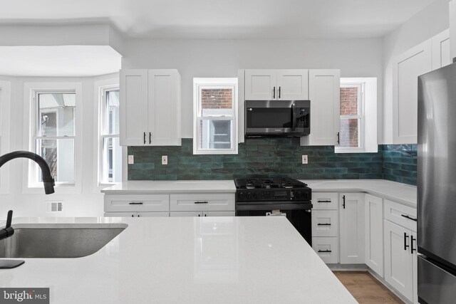 kitchen with white cabinets, stainless steel appliances, sink, and a healthy amount of sunlight