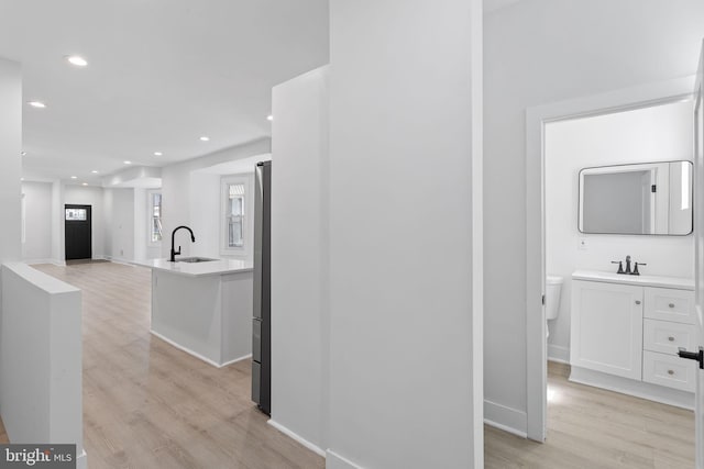 hallway featuring sink and light wood-type flooring