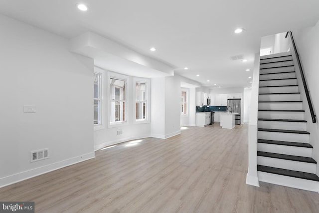 unfurnished living room with stairs, recessed lighting, visible vents, and light wood-style floors