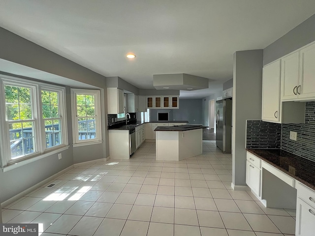 kitchen with a center island, light tile patterned floors, decorative backsplash, stainless steel appliances, and a sink