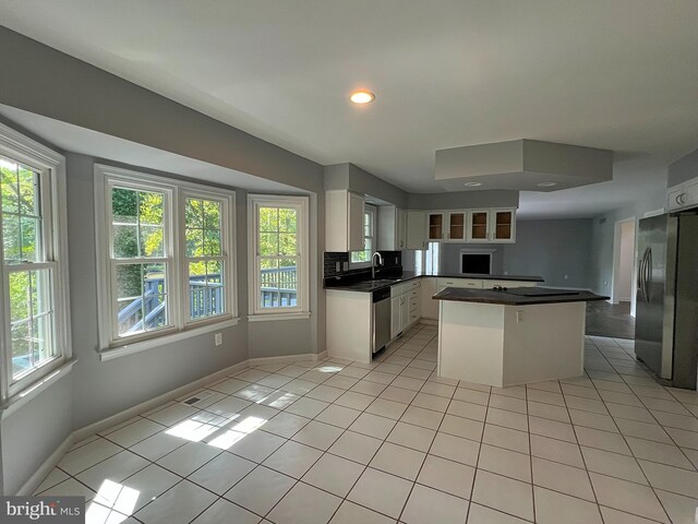 kitchen featuring dark countertops, light tile patterned floors, stainless steel appliances, white cabinetry, and a sink