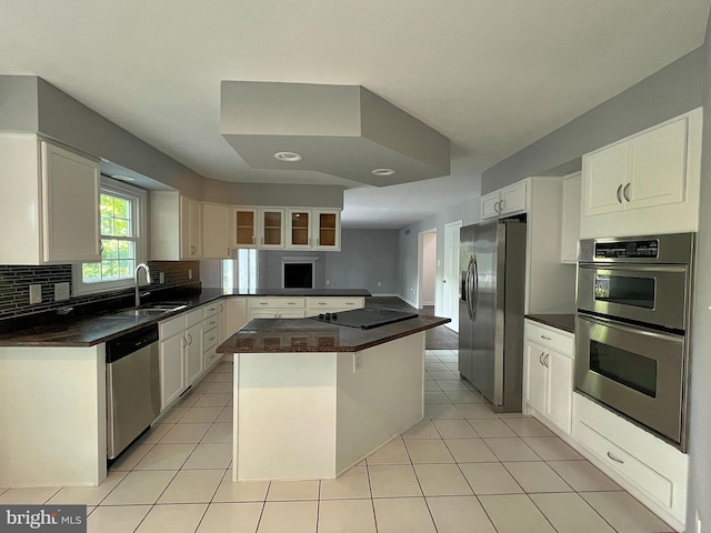 kitchen featuring backsplash, light tile patterned floors, appliances with stainless steel finishes, and a sink