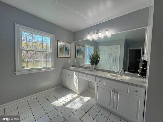 full bath with tile patterned floors, double vanity, baseboards, and a sink