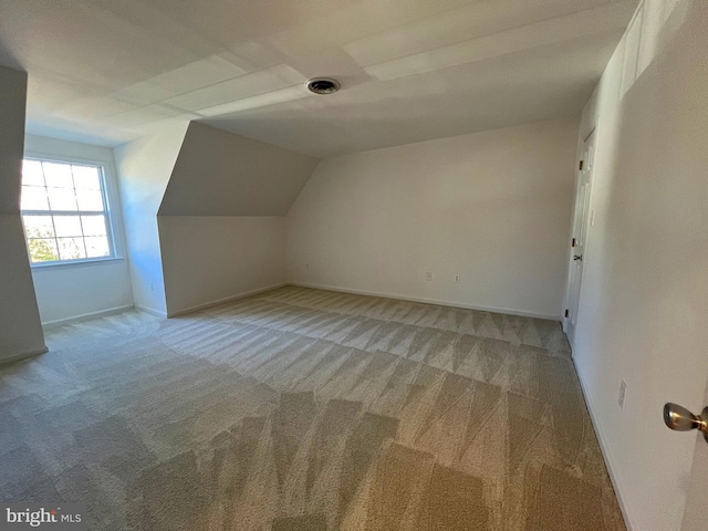 additional living space with lofted ceiling, light colored carpet, and baseboards