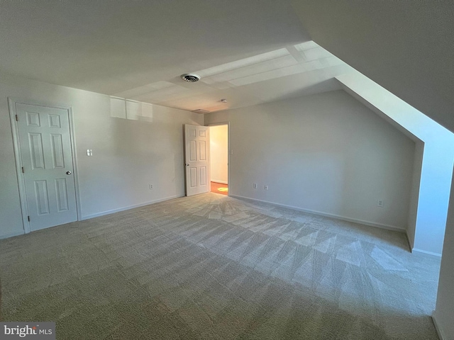 interior space with lofted ceiling, light colored carpet, visible vents, and baseboards