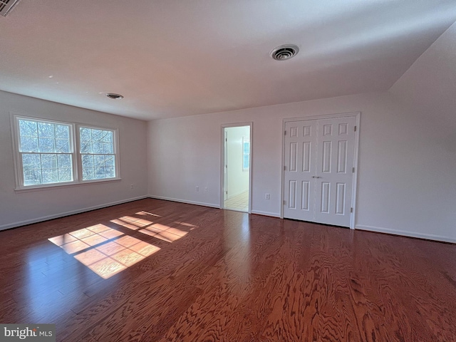 spare room with dark wood-type flooring, baseboards, and visible vents