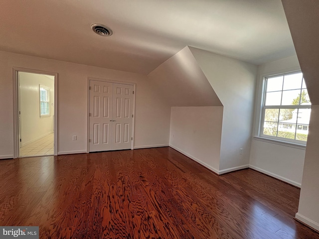 additional living space with visible vents, baseboards, lofted ceiling, and wood finished floors