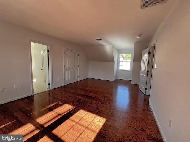 interior space with visible vents, baseboards, lofted ceiling, and wood finished floors