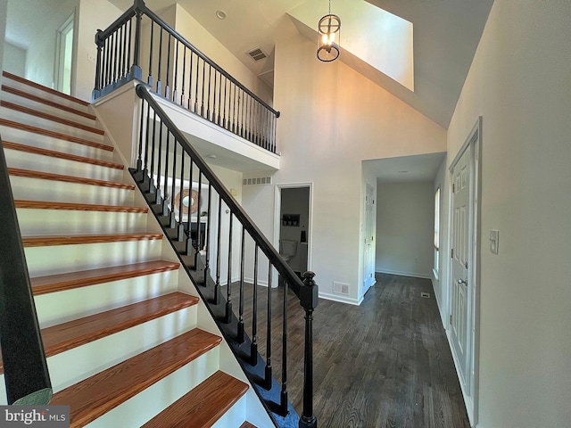 staircase featuring visible vents, high vaulted ceiling, baseboards, and wood finished floors