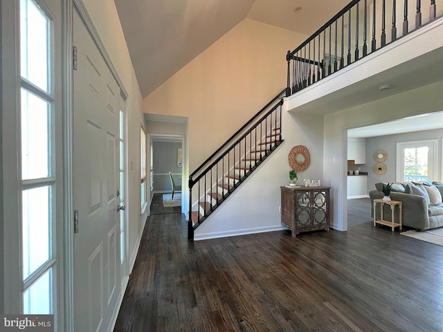 foyer with dark wood-style floors, high vaulted ceiling, stairs, and baseboards