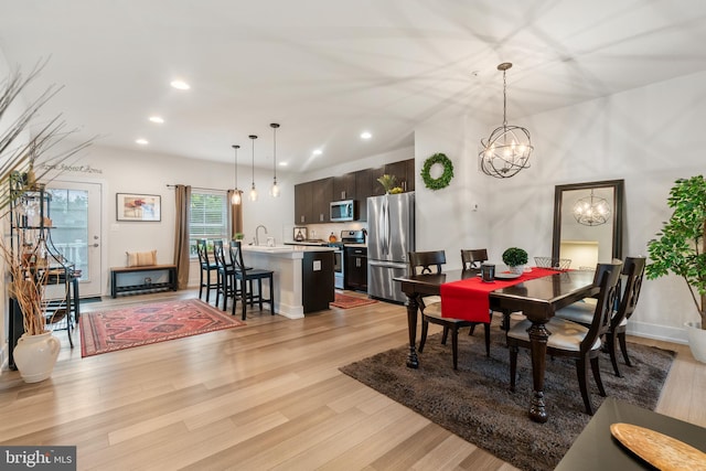 dining room featuring light wood finished floors, baseboards, an inviting chandelier, and recessed lighting