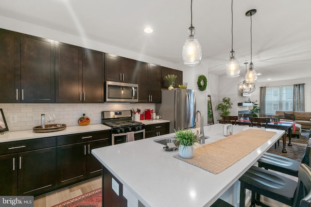 kitchen with a breakfast bar, decorative backsplash, stainless steel appliances, and a sink