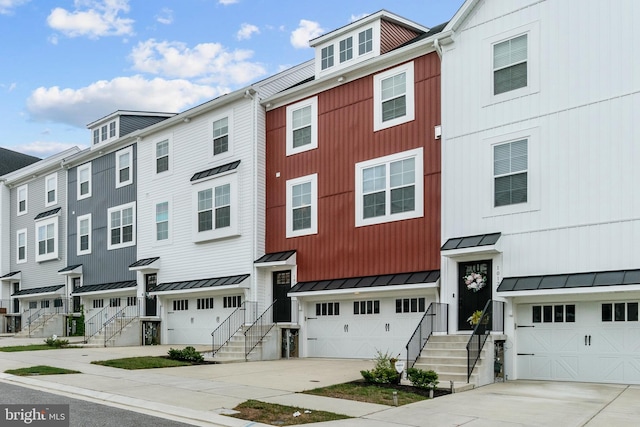 townhome / multi-family property featuring a garage, a standing seam roof, metal roof, and concrete driveway