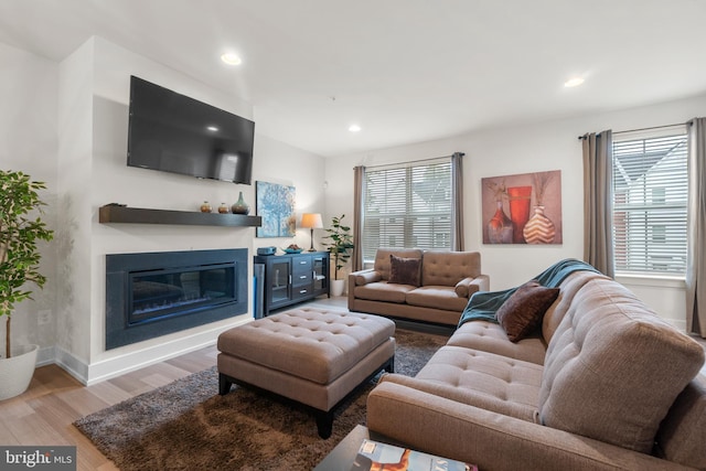 living area featuring recessed lighting, wood finished floors, a wealth of natural light, and a glass covered fireplace