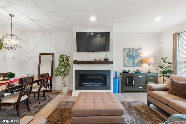 living area with a chandelier, wood finished floors, a glass covered fireplace, and recessed lighting