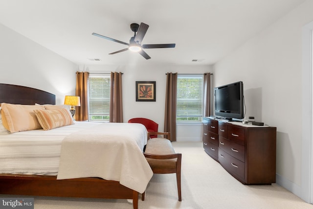 bedroom with ceiling fan, visible vents, baseboards, and light colored carpet