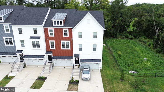 view of front of home featuring driveway, a shingled roof, metal roof, an attached garage, and a standing seam roof