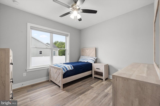 bedroom featuring a ceiling fan, baseboards, and light wood finished floors