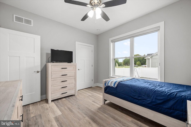 bedroom with ceiling fan, visible vents, baseboards, and light wood-style flooring