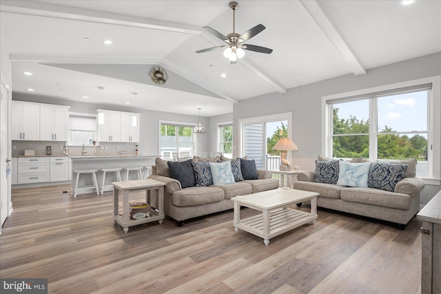 living room featuring ceiling fan, sink, vaulted ceiling with beams, and light hardwood / wood-style floors