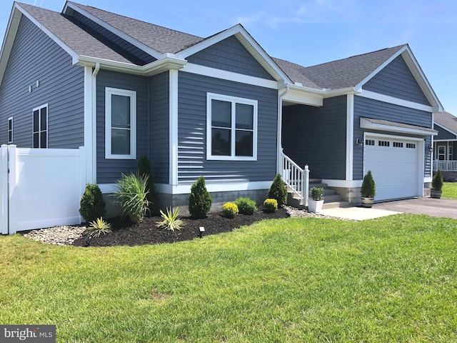 view of front of home featuring a front yard, a garage, driveway, and a shingled roof