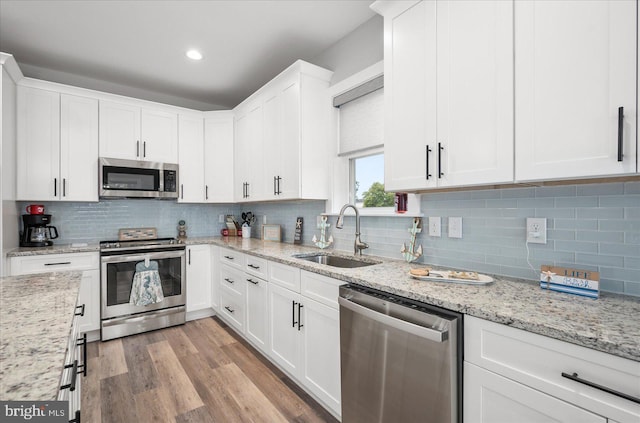 kitchen with a sink, light wood-style flooring, white cabinetry, and stainless steel appliances