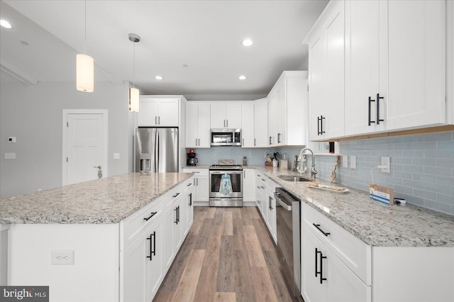 kitchen featuring light wood-type flooring, a sink, a kitchen island, stainless steel appliances, and decorative backsplash