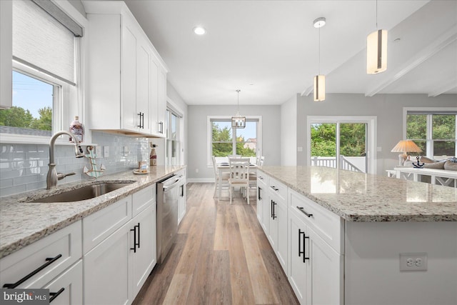 kitchen featuring light wood-style flooring, plenty of natural light, a sink, white cabinetry, and tasteful backsplash