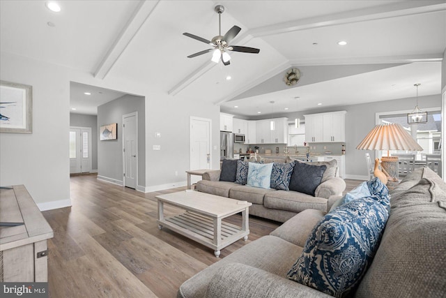 living room featuring ceiling fan, light wood-type flooring, and lofted ceiling with beams