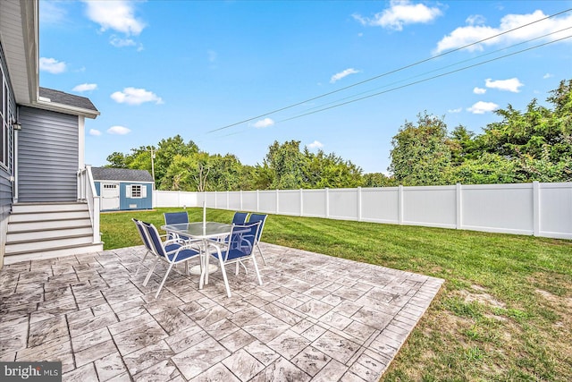 view of patio / terrace featuring a storage unit, a fenced backyard, an outdoor structure, and outdoor dining space