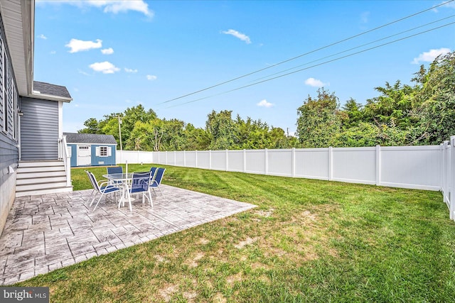 view of yard featuring a storage shed, an outbuilding, a fenced backyard, and a patio