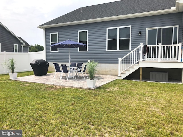 rear view of property with a yard, fence, a shingled roof, and a patio area