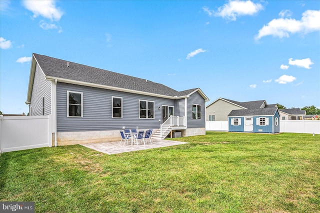 rear view of house with a patio, a yard, a fenced backyard, and a shingled roof