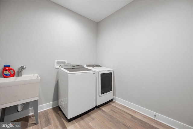 laundry room with separate washer and dryer and light hardwood / wood-style floors