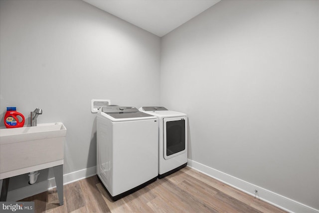 laundry area with baseboards, washing machine and dryer, laundry area, and light wood finished floors