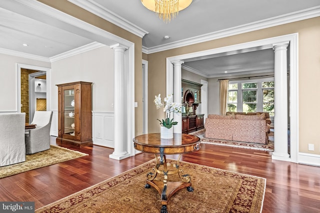 foyer entrance featuring ornamental molding, ornate columns, an inviting chandelier, and dark hardwood / wood-style floors