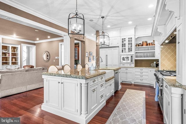 kitchen featuring decorative light fixtures, a center island with sink, stainless steel appliances, dark hardwood / wood-style floors, and white cabinetry