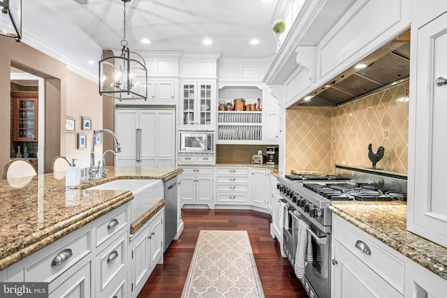 kitchen featuring dark wood-type flooring, decorative backsplash, hanging light fixtures, built in appliances, and white cabinetry