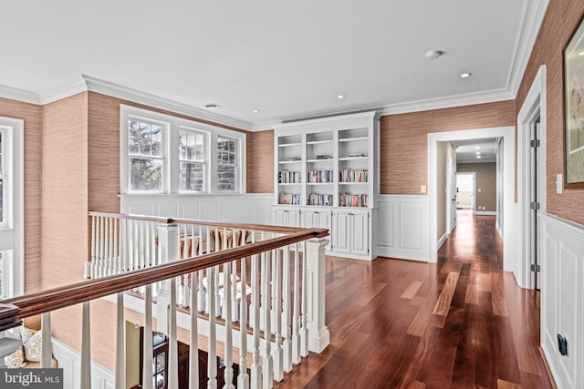 hall with dark wood-type flooring, built in features, and ornamental molding