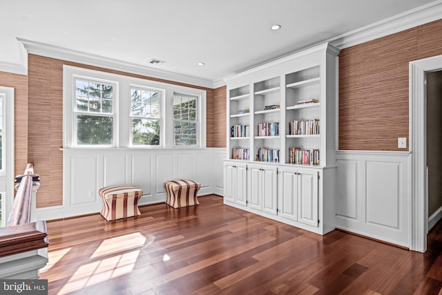 sitting room featuring ornamental molding, built in shelves, and dark hardwood / wood-style flooring