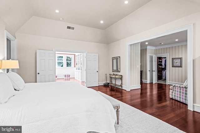 bedroom featuring lofted ceiling, a spacious closet, a closet, dark hardwood / wood-style floors, and crown molding