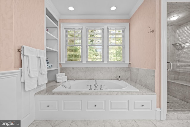 bathroom with ornamental molding and shower with separate bathtub